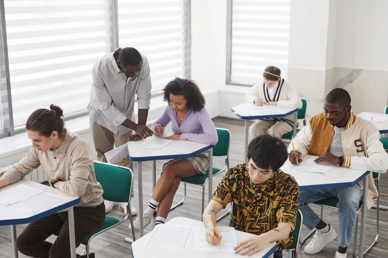 Candidates sitting a written certification exam under supervision in a classroom