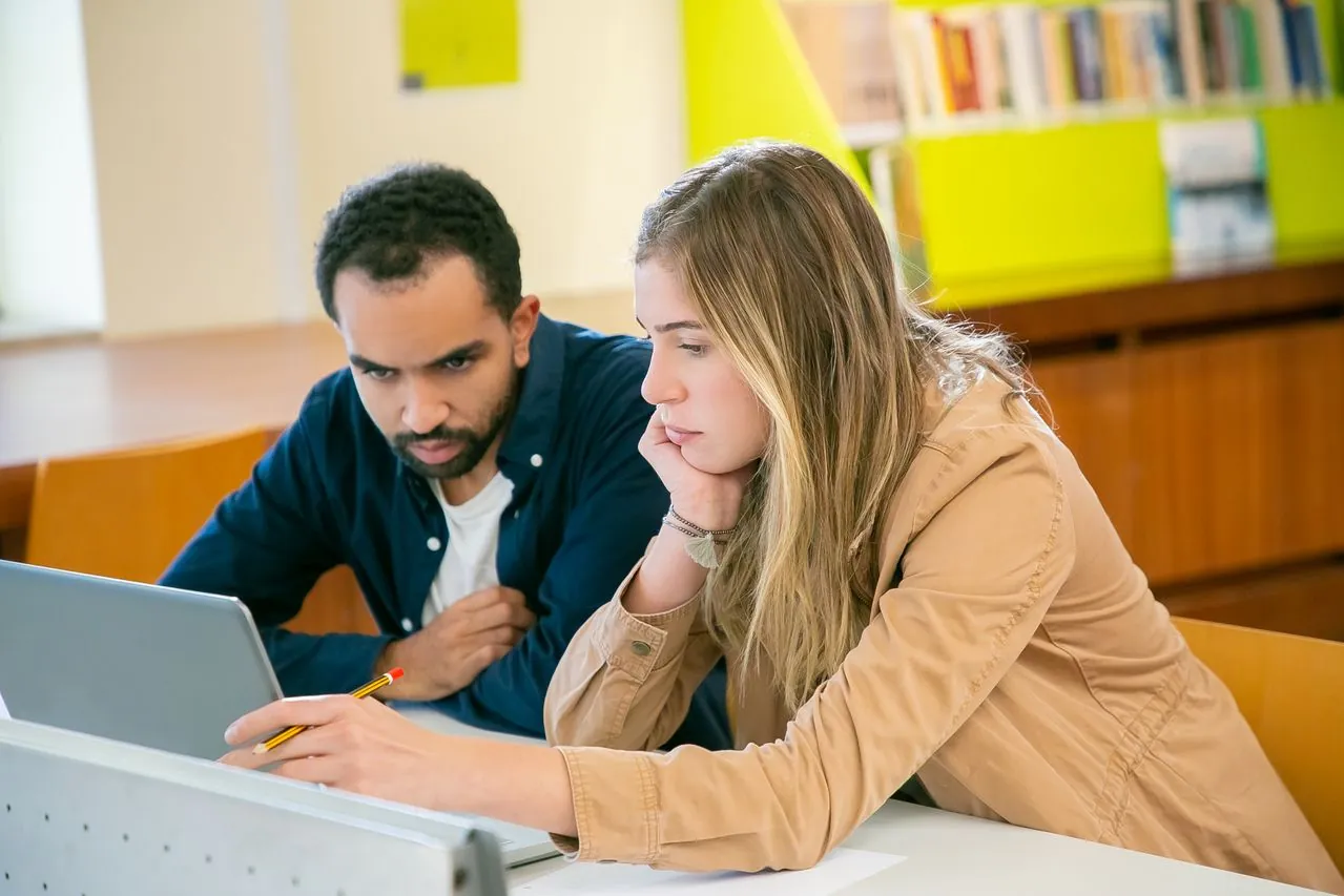 Ausbilder und duale Studentin bereiten sich gemeinsam am Laptop auf die IHK-Prüfung vor